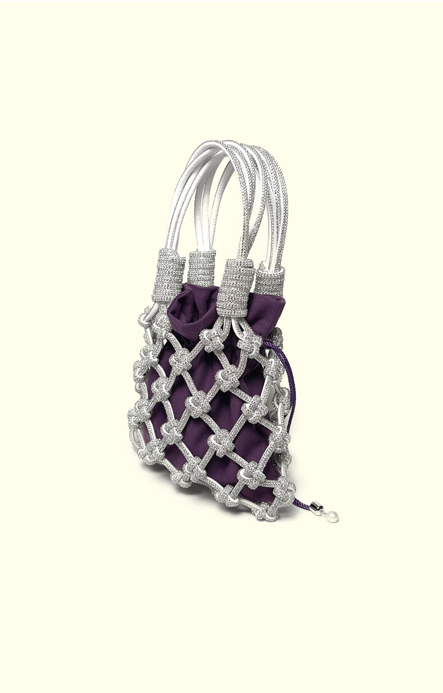 Purple cotton drawstring pouch inside a rhinestone net bag