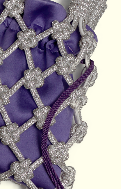 Purple satin drawstring pouch inside a rhinestone net bag