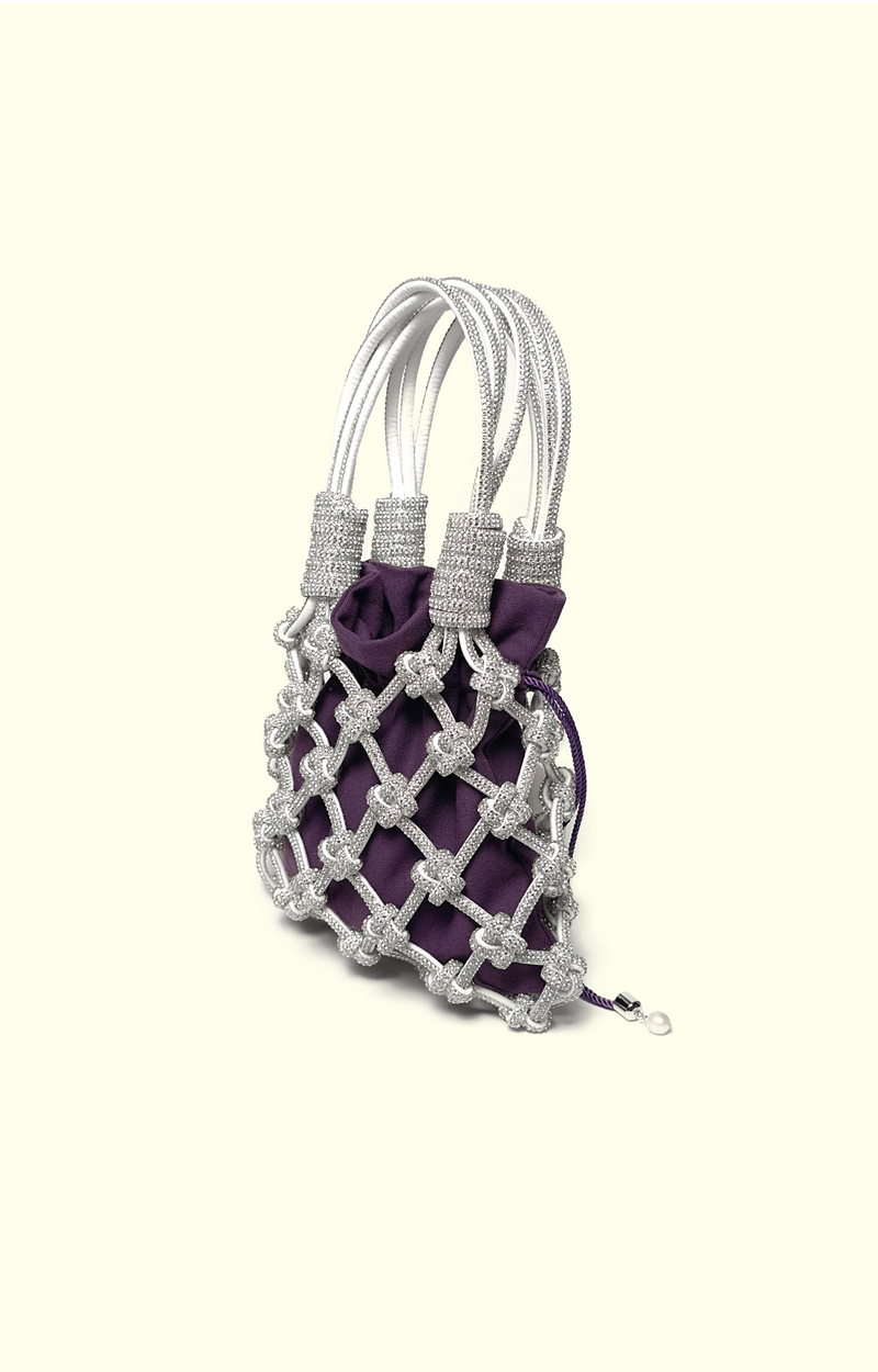 Purple cotton drawstring pouch inside a rhinestone net bag