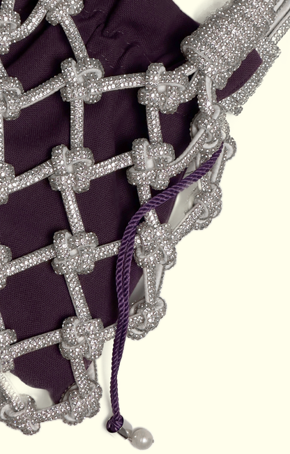 Purple cotton drawstring pouch inside a rhinestone net bag