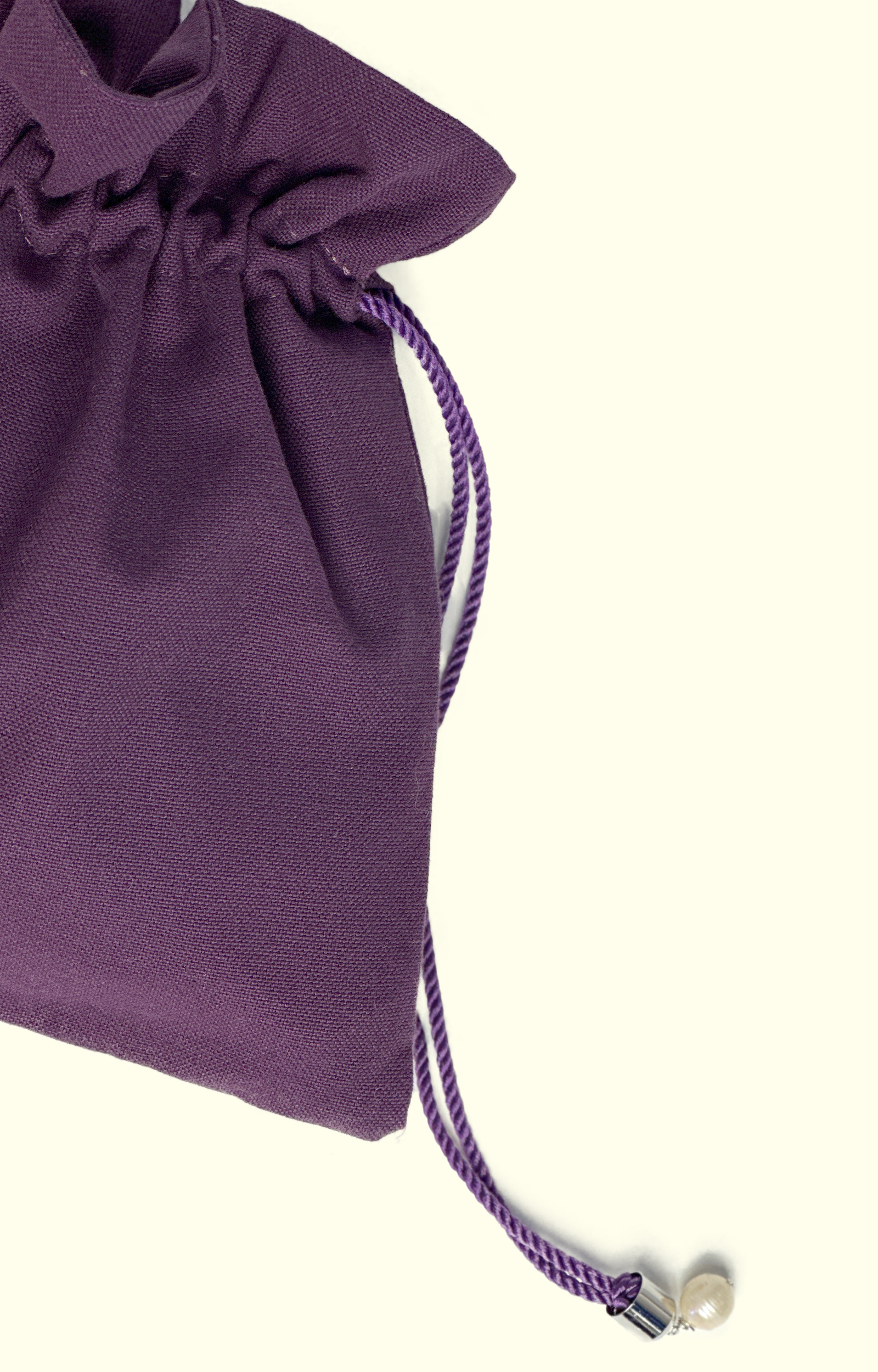 Purple drawstring bag with a pearl charm on a white background